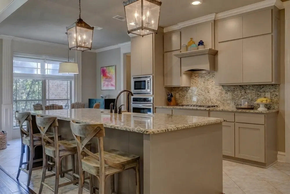 The same kitchen with the granite carried from the countertop up to the upper cabinets and the range hood, so counter and wall form one speckled surface