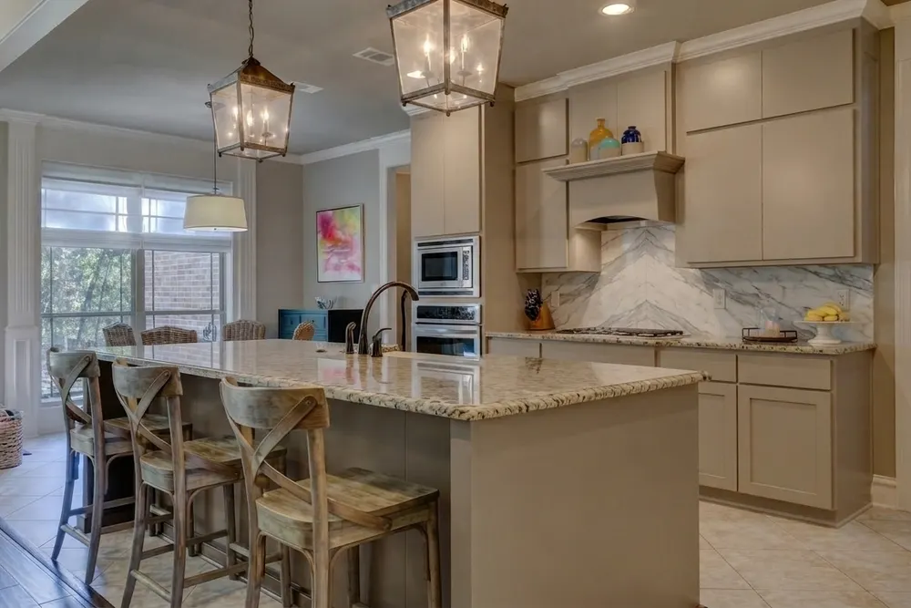 The same kitchen with a book-matched white marble backsplash with bold gray veining laid in a chevron that meets above the cooktop