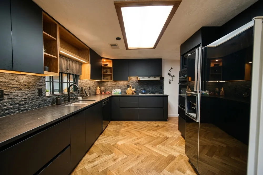 Narrow black U-shaped galley kitchen with one window and a skylight, black countertops on both sides
