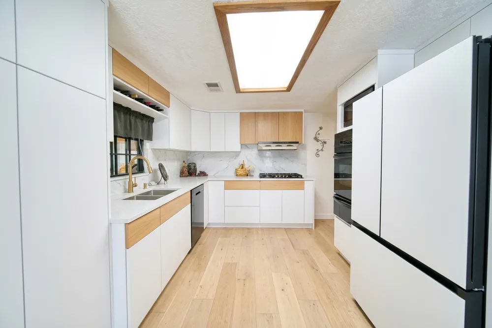 Flat-panel cool white cabinets with oak accent shelving and a wide-plank warm oak floor