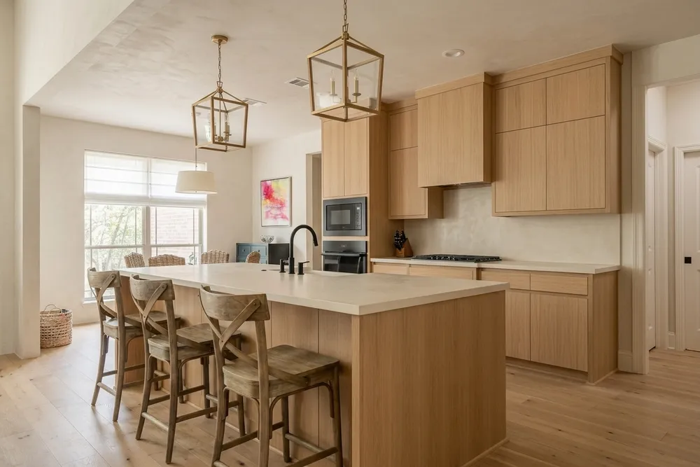 Light oak flat-panel kitchen cabinets and a pale wide-plank wood floor in the same island kitchen, close in tone