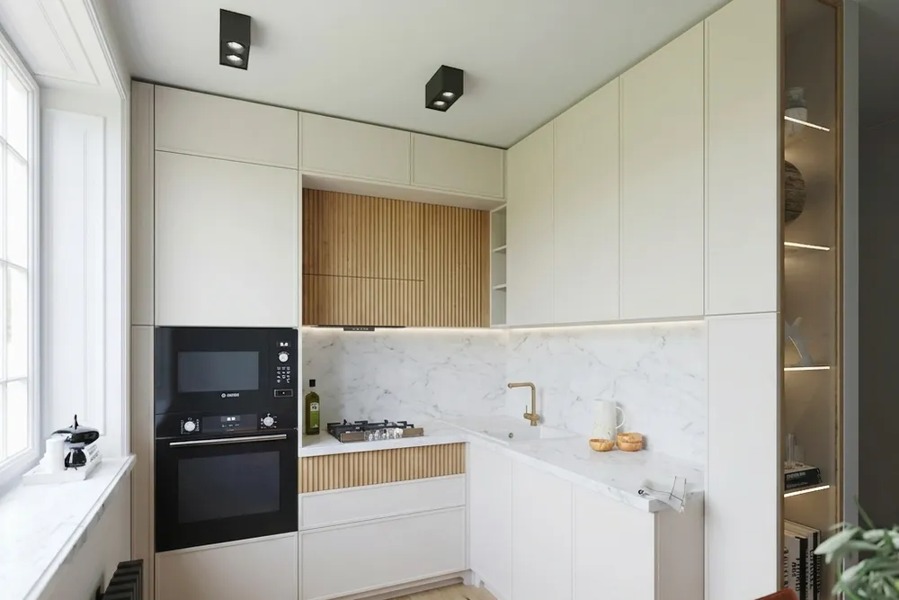 The same corner kitchen with cream flat cabinet fronts, a white marble-look countertop and backsplash, an oak fluted panel under the hood and a light line under the wall cabinets