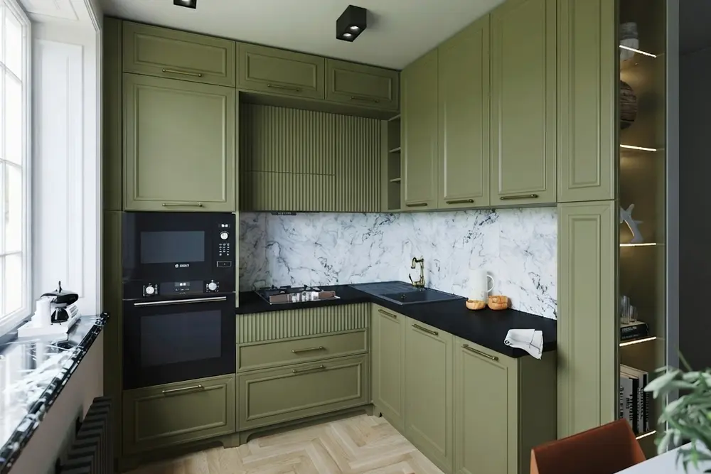 The same small kitchen with every cabinet in warm matte olive green, including the ribbed hood surround and the ribbed panel under the cooktop, with the black countertop, marble-look backsplash and herringbone floor unchanged