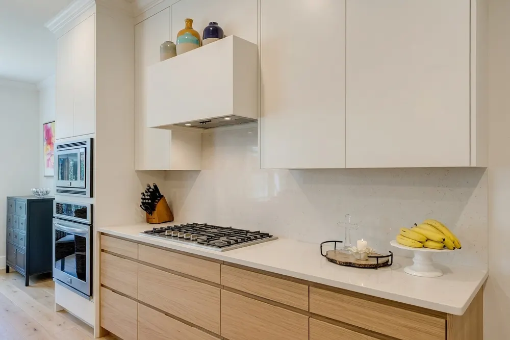 Dezelfde keukenwand met licht eiken fronten en een wit werkblad